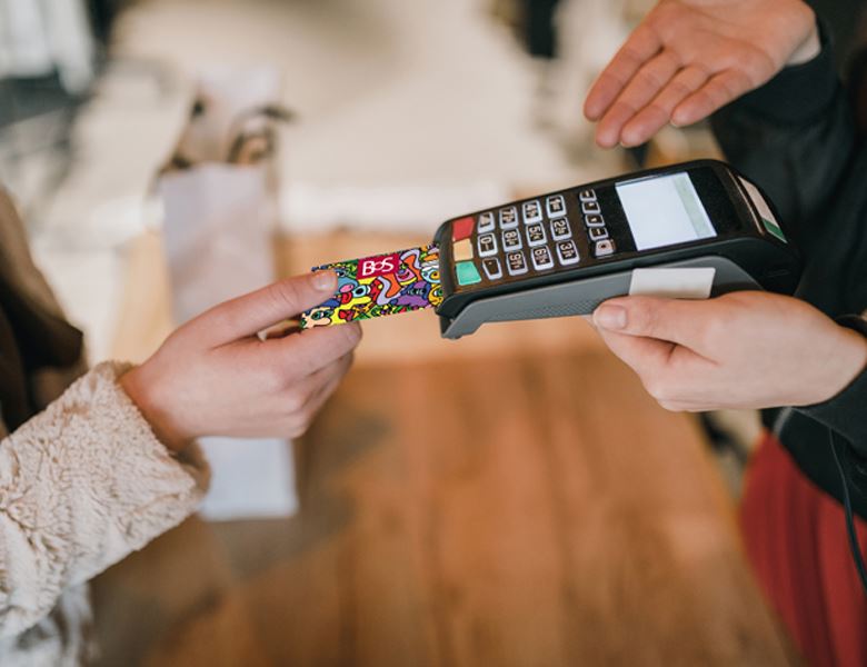 A close-up of a girl using a BOS debit card in a point of sales terminal.