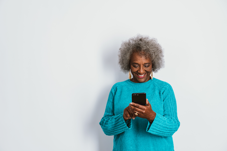 A senior citizen checking her mobile phone and smiling.