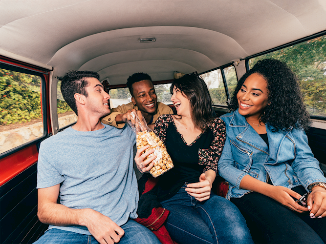 A group of friends laughing while on a roadtrip.
